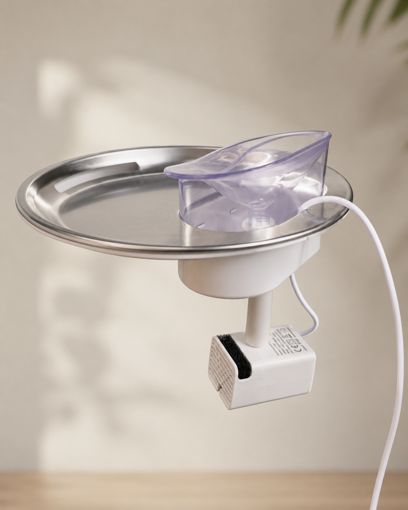 The HydroBuddy pump with its white power cord clicked under the stainless steel plate with the clear spout on top